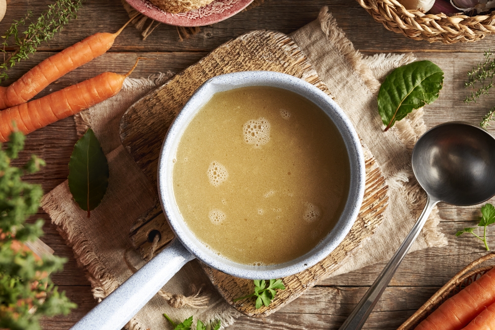 Chicken,Bone,Broth,In,A,Blue,Saucepan,With,Fresh,Vegetables