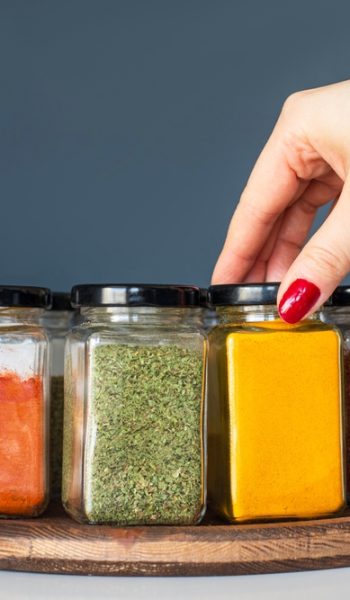 Cropped,Hand,Holding,Jar,Of,Spices,On,Kitchen.